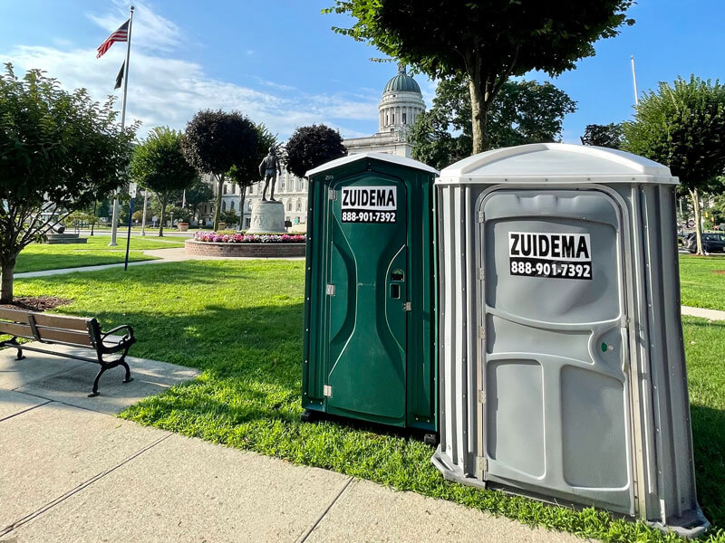 Crane lifting a portable restroom for rental service in NJ & NY